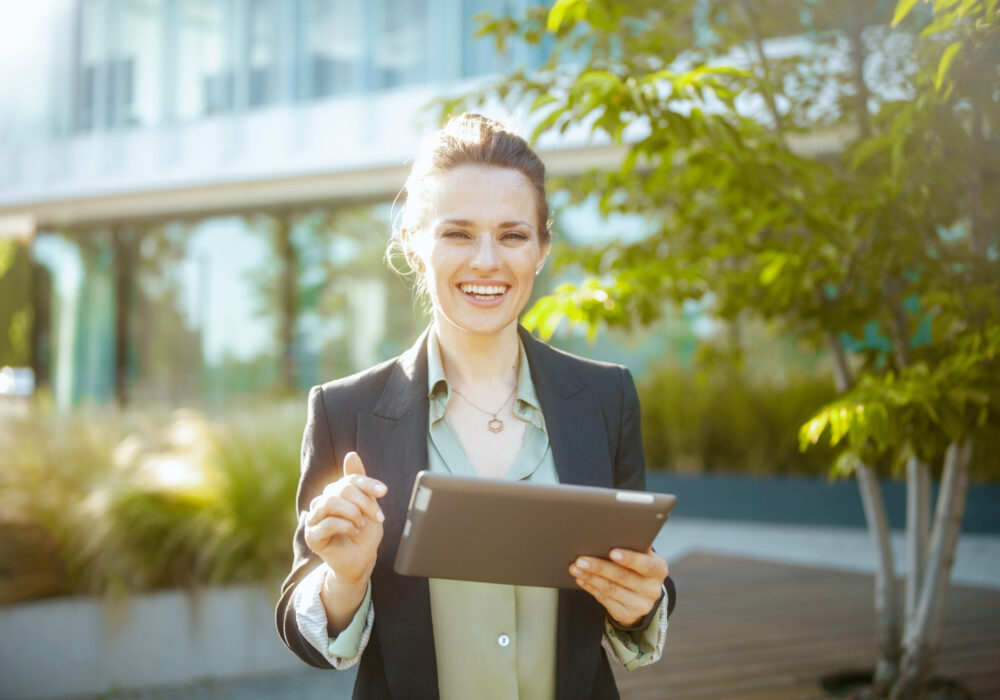smiling 40 years old woman employee near business center smiling modern 40 years old woman employee near business center in black jacket with tablet PC.